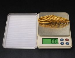 Guldarmband som vägs på en digital precisionsvåg för att sälja guld.