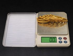 Guldarmband som vägs på en digital precisionsvåg för att sälja guld.
