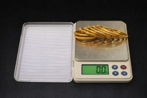 Guldarmband som vägs på en digital precisionsvåg för att sälja guld.