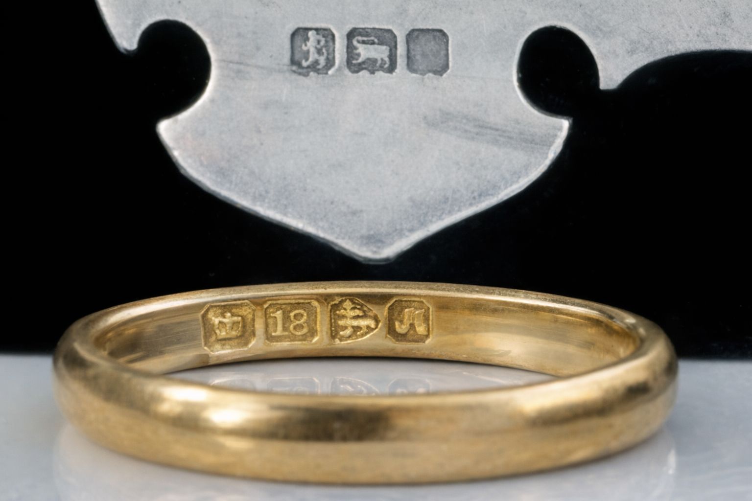 Närbild på kontrollstämplar i en guldring och på ett silverföremål.