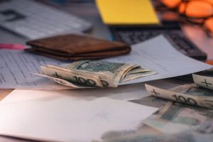 Sedlar, en plånbok och dokument på ett skrivbord som visar företagets kassaflöde.